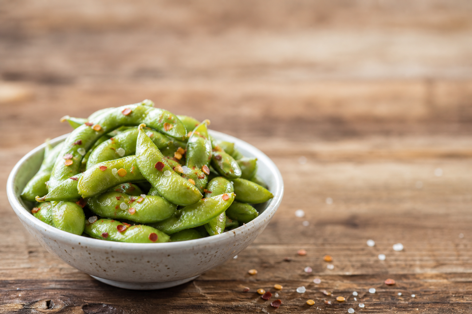 Gyldne edamame-bælge med salt og chiliflak i lille skål